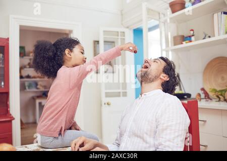 Süße Tochter, die Vater Traube füttert Stockfoto