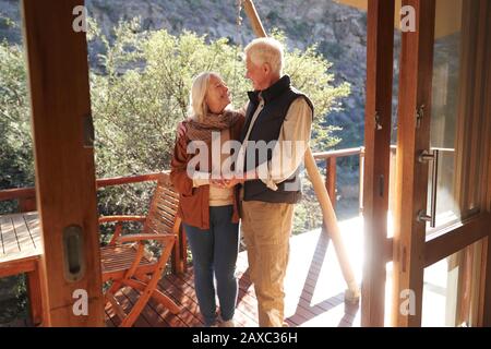 Fröhliches liebevolles Senioren-Paar auf dem sonnigen Safari-Lodge-Balkon Stockfoto