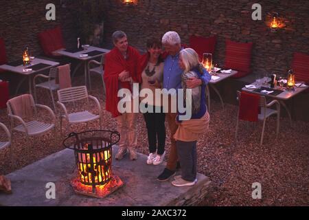 Fröhliche ältere Freunde, die sich im Feuergraben auf der Hotelterrasse entspannen Stockfoto