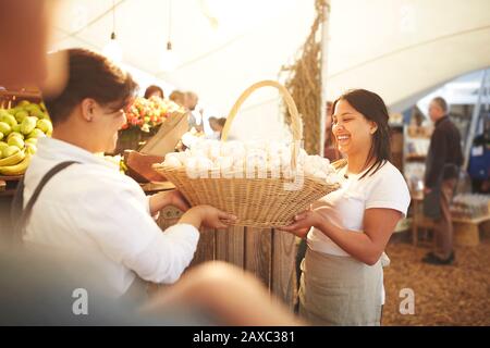 Frauen, die einen Korb frischen Knoblauchs auf dem Bauernmarkt tragen Stockfoto