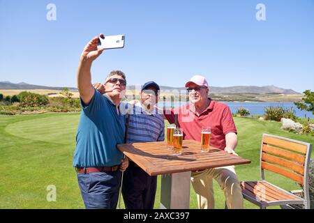 Männliche Freunde, die Bier trinken und selfie auf der Terrasse des Golfplatzes einnehmen Stockfoto