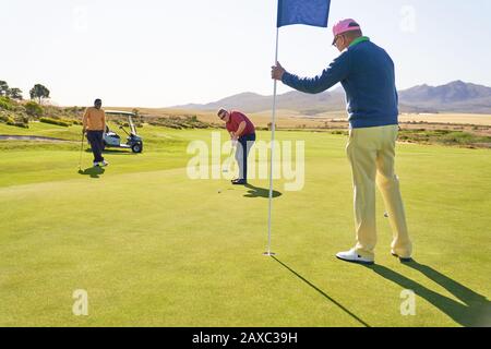 Männer auf dem sonnigen Golf, das Grün setzt Stockfoto