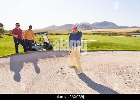 Senior man schießt auf einem sonnigen Golfplatz aus dem Bunker Stockfoto