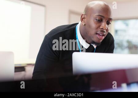 Konzentrierter männlicher Lehrer am Computer im Klassenzimmer Stockfoto