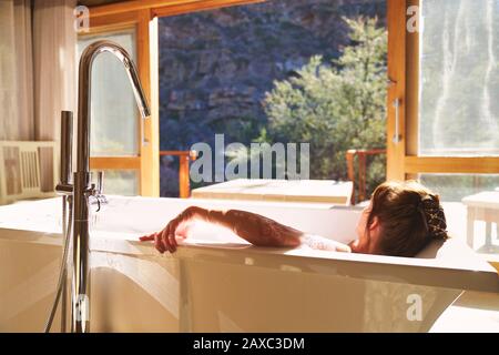 Ruhige Frau, die im sonnigen Hotelzimmer baden kann Stockfoto