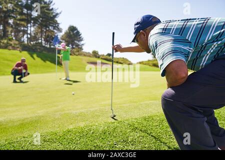 Männlicher Golfer, der sich auf einem sonnigen Golfplatz abputzt Stockfoto