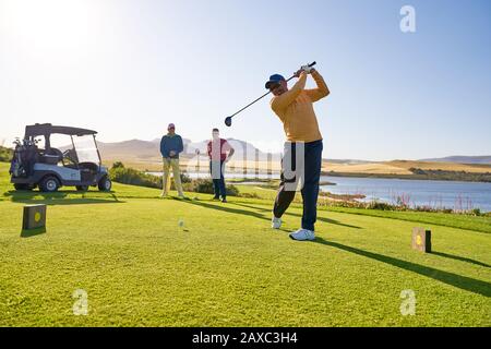 Männlicher Golfer, der an der sonnigen Golf-T-Box abzweigte Stockfoto