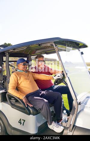 Reife männliche Golfer, die in der Golfkarre reiten Stockfoto