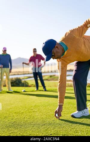 Männlicher Golfer, der sich am sonnigen Golf-T-Stück-Kasten abzweigen vorbereitet Stockfoto