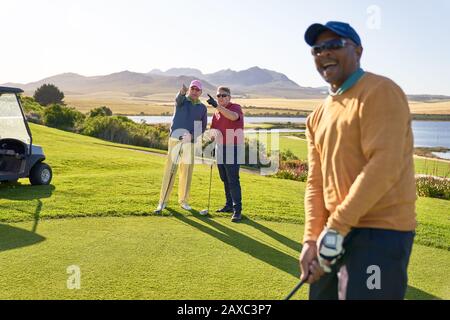 Männliche Golfer, die auf einem sonnigen Golfplatz sprechen Stockfoto