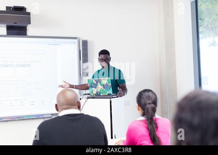 Lehrer der männlichen Community unterrichten Unterricht am Laptop und Projektionsleinwand im Klassenzimmer Stockfoto