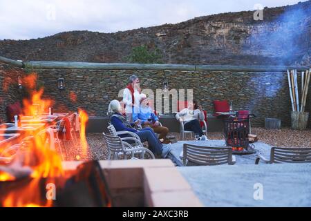 Senioren-Freunde entspannen mit Rotwein auf der Hotelterrasse mit Feuerstelle Stockfoto