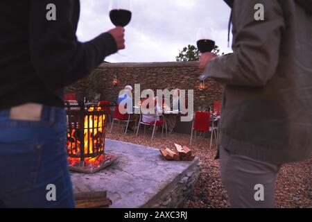 Paare und ältere Freunde, die auf der Terrasse mit Feuerstelle Wein trinken Stockfoto