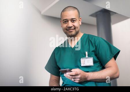 Portrait selbstbewusster, lächelnder männlicher Chirurg mit Smartphone Stockfoto