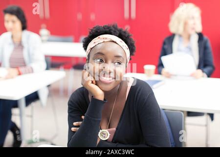 Lächelnde, selbstbewusste junge Community College-Studentin im Klassenzimmer