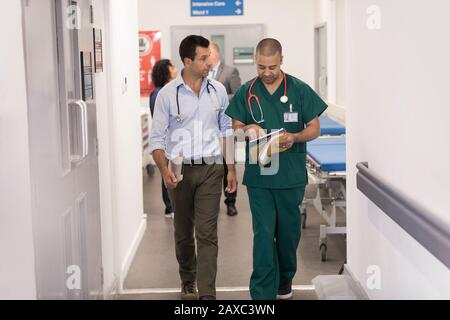 Männlicher Arzt und Chirurg mit medizinischer Karte, die Runden im Krankenhauskorridor führt Stockfoto