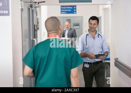 Männliche Ärzte grüßen, sich im Krankenhauskorridor vorbeiziehen Stockfoto