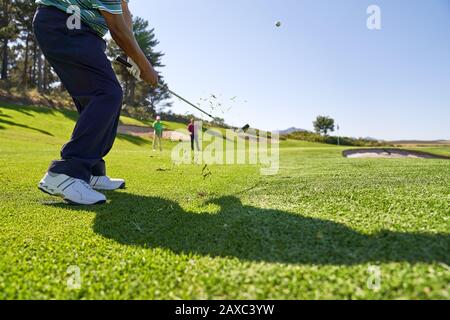 Männlicher Golfer, der auf einem sonnigen Golfplatz einen Schuss abschießt Stockfoto