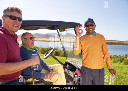 Portrait fröhlicher, selbstbewusster Golfer, der auf einem sonnigen Golfplatz gesturft ist Stockfoto