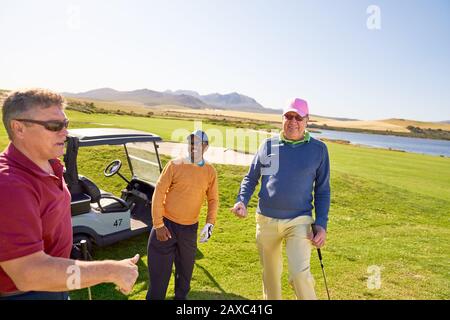 Glückliche männliche Golfer Freunde auf sonnigen Golfplatz Stockfoto