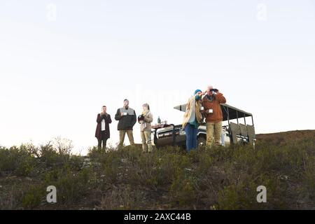 Safari-Tour-Gruppe, die Tee trinkt und Ferngläser auf dem Hügel verwendet Stockfoto