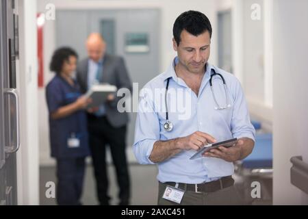 Hausarzt mit digitaler Tablette im Krankenhausflur Stockfoto