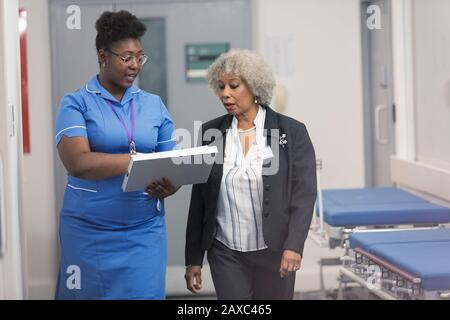 Ärztin und Krankenschwester diskutieren über die Krankenakte und machen Runden im Krankenhauskorridor Stockfoto