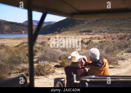 Älteres Paar auf Safari, das Zebras in der Ferne Südafrika beobachtet Stockfoto