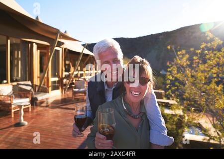 Portrait fröhliches älteres Paar, das Eistee auf dem sonnigen Hotelbalkon trinkt Stockfoto