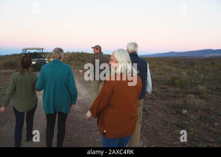 Glückliche Seniorin auf Safari, die mit der Gruppe ins Fahrzeug zurückkehrt Stockfoto