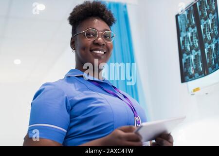 Portrait selbstbewusste Krankenschwester mit digitaler Tablette zur Untersuchung von Röntgenbildern im Krankenhausraum Stockfoto