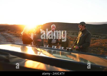 Safari-Tour-Gruppe, die Champagner bei Sonnenuntergang trinkt Stockfoto