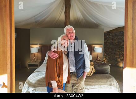 Portrait glückliches älteres Paar, das sich im Hotelzimmer der Safari-Lodge umarmt Stockfoto