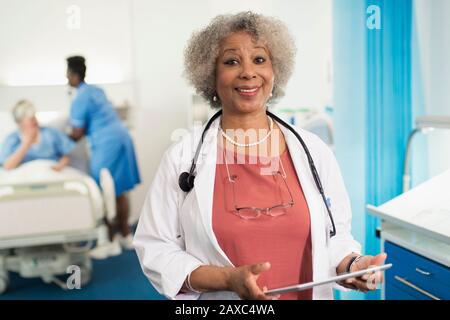 Hochsicherer leitender weiblicher Arzt mit digitaler Tablette im Krankenhauszimmer Stockfoto