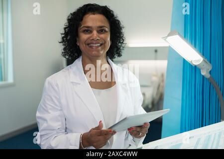 Portrait selbstbewusster, lächelnder weiblicher Arzt mit digitaler Tablette im Krankenhauszimmer Stockfoto