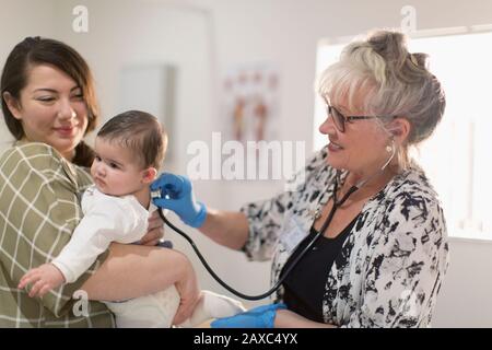 Kinderärztin mit Stethoskop untersucht Baby im Untersuchungsraum Stockfoto