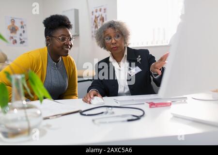Weibliche Ärztin, die sich mit dem Patienten am Computer in der Arztpraxis zusammentat Stockfoto