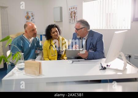 Ärzte und Administrator verwenden digitale Tabletts und treffen sich im Büro der Ärzte Stockfoto