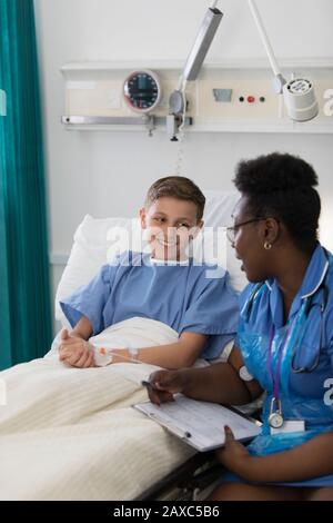 Weibliche Krankenschwester spricht mit einer Patientin im Krankenhauszimmer Stockfoto