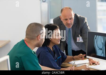 Ärzte und Pfleger untersuchen Röntgenaufnahmen am Computer in der Klinik Stockfoto