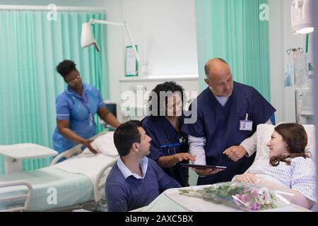 Ärzte mit digitaler Tablette runden das Gespräch mit dem Patienten auf der Krankenstation ab Stockfoto