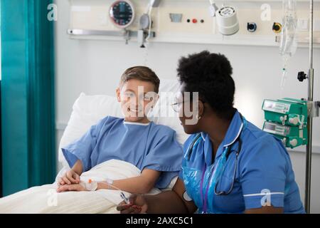 Weibliche Krankenschwester spricht mit einer Patientin im Krankenhauszimmer Stockfoto