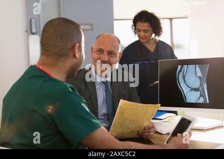 Arzt und Pfleger diskutieren über digitales Röntgen am Computer in der Klinik Stockfoto