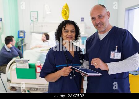 Hochformatige Ärzte mit digitaler Tablette runden das Krankenhauszimmer ab Stockfoto