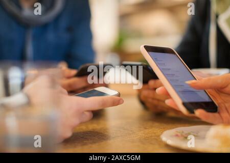 Junge Erwachsene, die Smartphones am Tisch nutzen Stockfoto