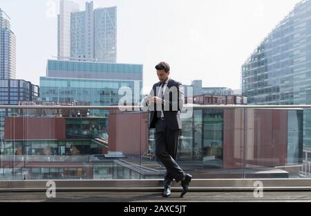 Geschäftsmann mit Smartphone auf sonnigen städtischen Balkon, Shoredisch, London Stockfoto