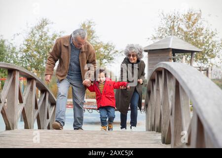Großeltern, die mit Grandson auf einer Fußgängerbrücke spazieren Stockfoto