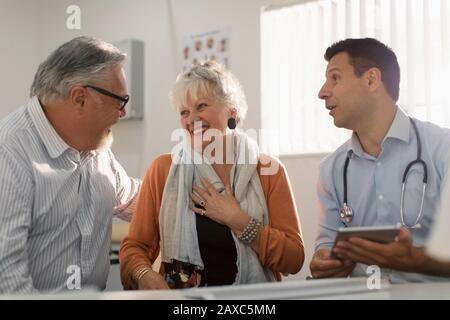 Arztbesprechung mit einem glücklichen Senioren-Paar in der Arztpraxis Stockfoto