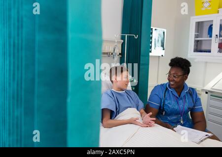 Weibliche Krankenschwester spricht mit einer Patientin im Krankenhauszimmer Stockfoto