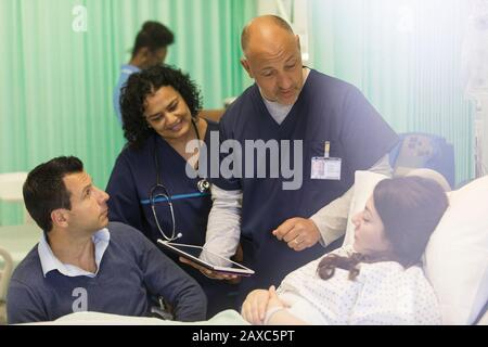 Ärzte mit digitaler Tablette runden das Gespräch mit dem Patienten auf der Krankenstation ab Stockfoto